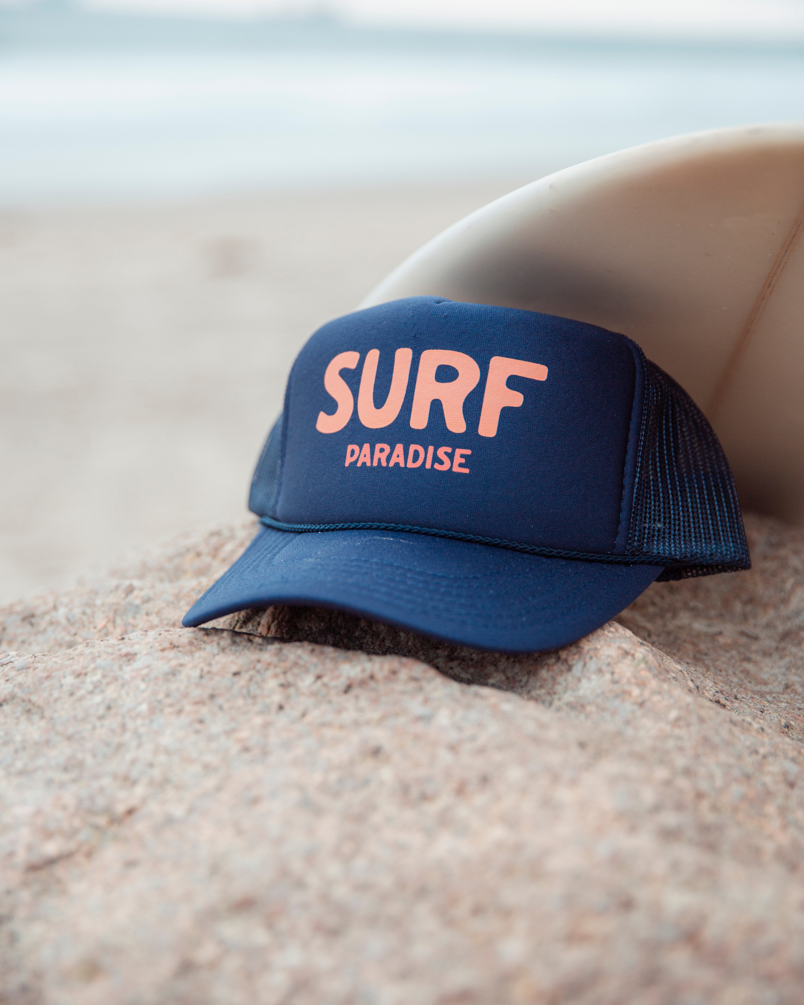 Blue trucker hat with 'SURF PARADISE' text on front