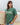 A person standing on a beach holding a surfboard and wearing a green t-shirt with the text 'ZIPPERS' printed on it.